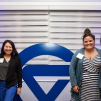 4 women pose together in front of a GVSU logo sign